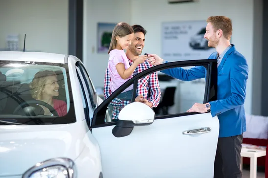 Sales manager at a showroom car with young family as buyers